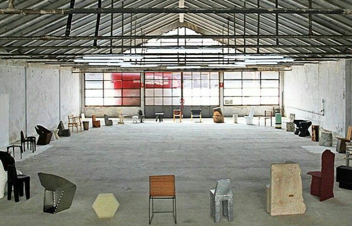 Espace de workshop dans un ancien entrepôt avec des chaises disposées en cercle en attente des participants.