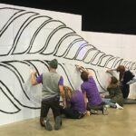 Équipe réalisant un scribing sur un mur Velleda de 10 mètres composé de cubes Tetrix, dessinant une feuille de fougère symbole de la Nouvelle-Zélande