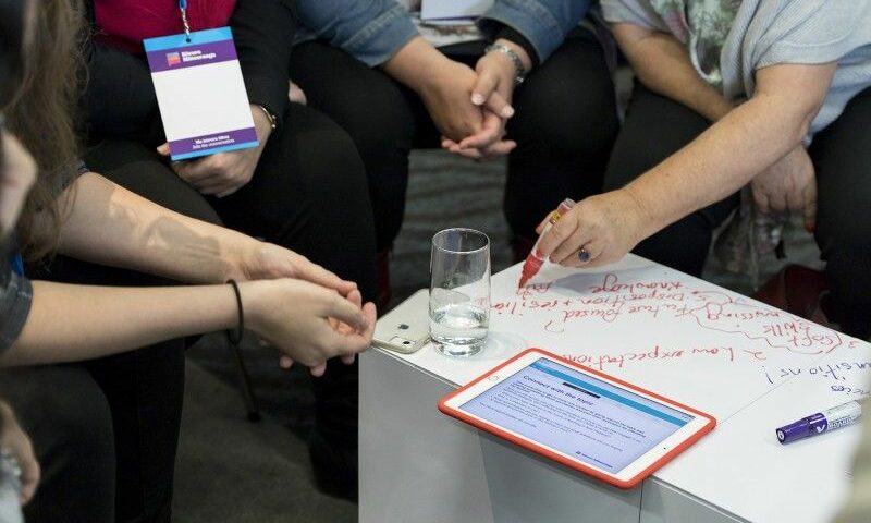 Participants en atelier collaboratif assis autour d’une table modulaire Tetrix recouverte de panneaux Velleda, prenant des notes directement sur la surface de travail.